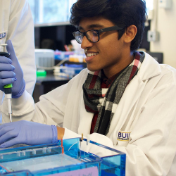 SF BUILD scholar in a white coat using a pipette.