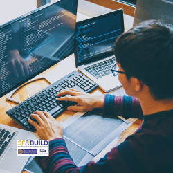 A student facing a desktop with hands on keyboard, working on their code.