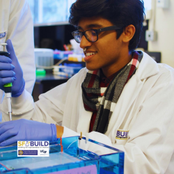 An SF BUILD scholar in a white lab coat using a pipette to put substance in a petri dish.