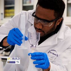 A student holding transferring liquid from a test tube to a flask.