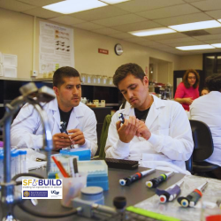 Two male scientist inspecting an apparatus in a lab.