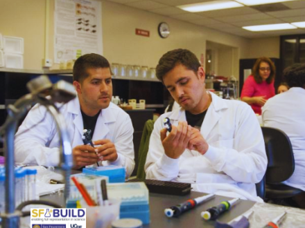 Two male scientist inspecting an apparatus in a lab.